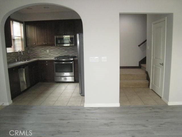 908 Grove Ct, Claremont, CA 91711 - kitchen featuring appliances with stainless steel finishes, a sink, arched walkways, and light tile patterned floors