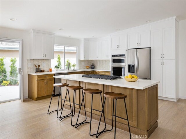 4918 Delacroix Rd, Rancho Palos Verdes, CA 90275 - kitchen with appliances with stainless steel finishes, light wood-type flooring, decorative backsplash, white cabinetry, and light countertops