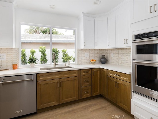 4918 Delacroix Rd, Rancho Palos Verdes, CA 90275 - kitchen with stainless steel appliances, light countertops, light wood-style flooring, white cabinetry, and backsplash