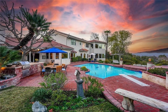 25578 Via Paladar, Valencia, CA 91355 - pool at dusk featuring exterior kitchen, a patio, and an outdoor pool