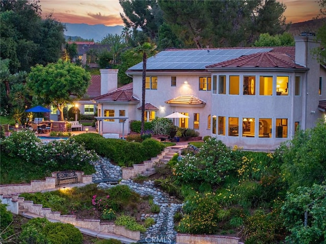 25578 Via Paladar, Valencia, CA 91355 - back of house at dusk featuring stairs, stucco siding, a chimney, and a tiled roof