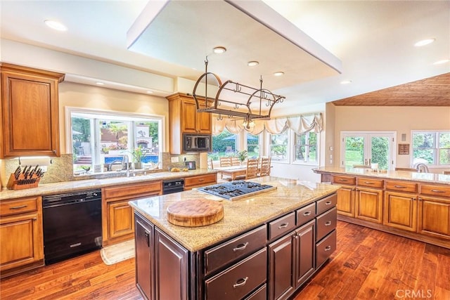 25578 Via Paladar, Valencia, CA 91355 - kitchen featuring black dishwasher, a kitchen island, wood-type flooring, light stone countertops, and backsplash