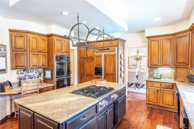 25578 Via Paladar, Valencia, CA 91355 - kitchen with stainless steel gas cooktop, light stone countertops, dark wood-type flooring, brown cabinets, and recessed lighting