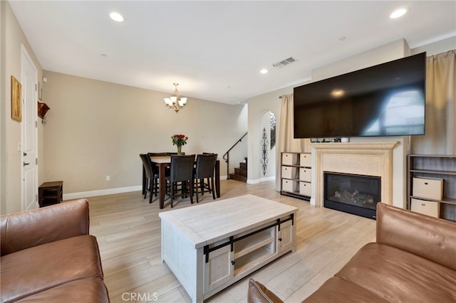 7021 Passons Blvd, Pico Rivera, CA 90660 - living room with a chandelier, light wood-style flooring, a glass covered fireplace, recessed lighting, and stairs