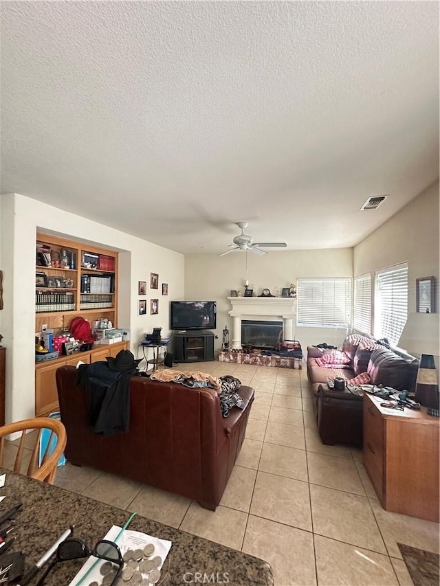 1612 Via Colabria, Gustine, CA 95322 - living area featuring ceiling fan, light tile patterned floors, a glass covered fireplace, and a textured ceiling