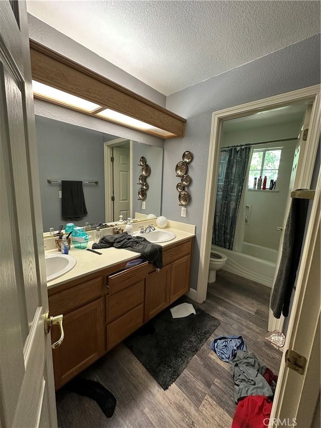1612 Via Colabria, Gustine, CA 95322 - full bath with double vanity, wood finished floors, shower / tub combo with curtain, toilet, and a textured ceiling