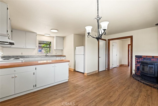490 Vilas Rd, Chico, CA 95973 - kitchen with freestanding refrigerator, a sink, a wood stove, light wood finished floors, and a chandelier