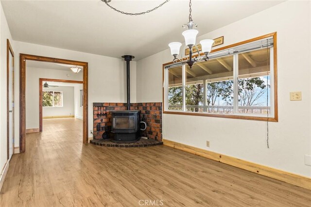 490 Vilas Rd, Chico, CA 95973 - unfurnished living room featuring a wood stove, wood finished floors, baseboards, and a chandelier