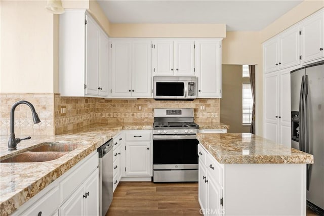 24952 Eaton Ln, Laguna Niguel, CA 92677 - kitchen featuring appliances with stainless steel finishes, a center island, light stone countertops, white cabinets, and backsplash