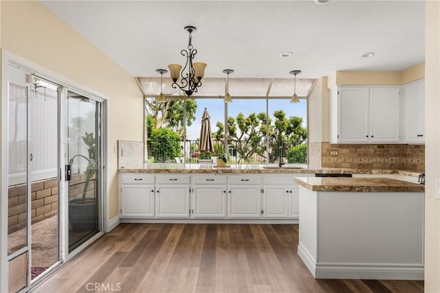 24952 Eaton Ln, Laguna Niguel, CA 92677 - kitchen with dark wood finished floors, white cabinetry, decorative backsplash, a chandelier, and light stone counters