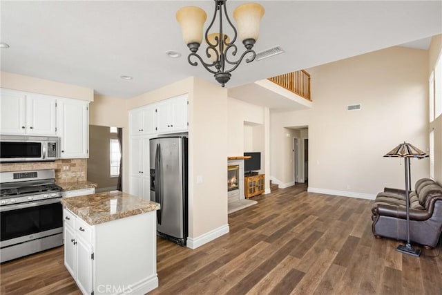 24952 Eaton Ln, Laguna Niguel, CA 92677 - kitchen featuring stainless steel appliances, open floor plan, a chandelier, light stone countertops, and white cabinets