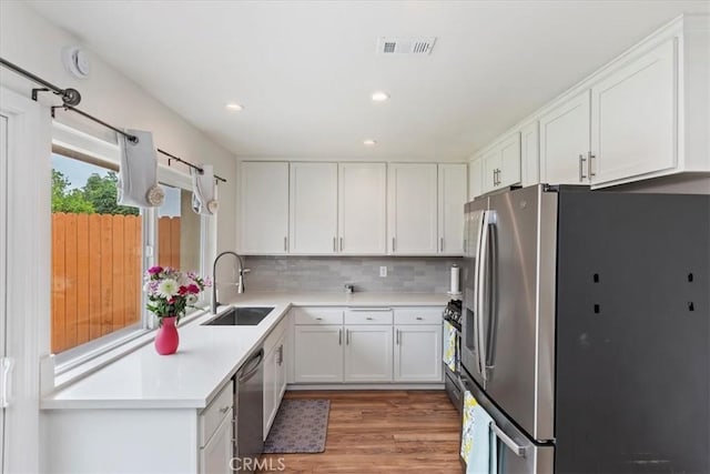 22554 Pico St, Grand Terrace, CA 92313 - kitchen featuring stainless steel appliances, a sink, light wood-style floors, white cabinets, and tasteful backsplash