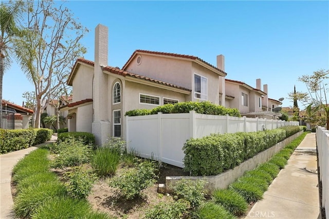 1 Buttercup Unit 42, Rancho Santa Margarita, CA 92688 - view of side of home with a chimney, a tiled roof, and stucco siding