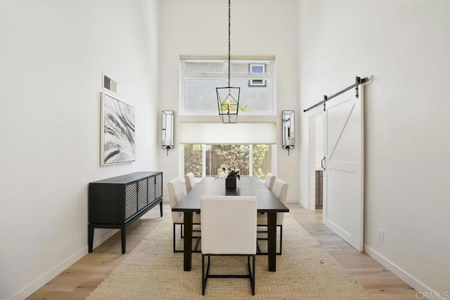 5233 Belardo Dr, San Diego, CA 92124 - dining area featuring a high ceiling, a barn door, and light wood finished floors