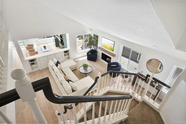 5233 Belardo Dr, San Diego, CA 92124 - living area with a lit fireplace, light wood-style flooring, and stairway