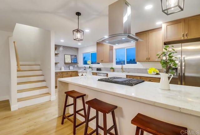 3776 Enero Ct, San Diego, CA 92154 - kitchen featuring island exhaust hood, stainless steel appliances, light wood finished floors, a kitchen bar, and recessed lighting