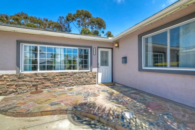 2581 Meadow Lark Dr, San Diego, CA 92123 - view of exterior entry with stucco siding, a patio, and stone siding