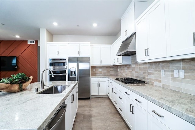 173 Biome, Irvine, CA 92618 - kitchen with stainless steel appliances, under cabinet range hood, white cabinetry, light stone countertops, and tasteful backsplash