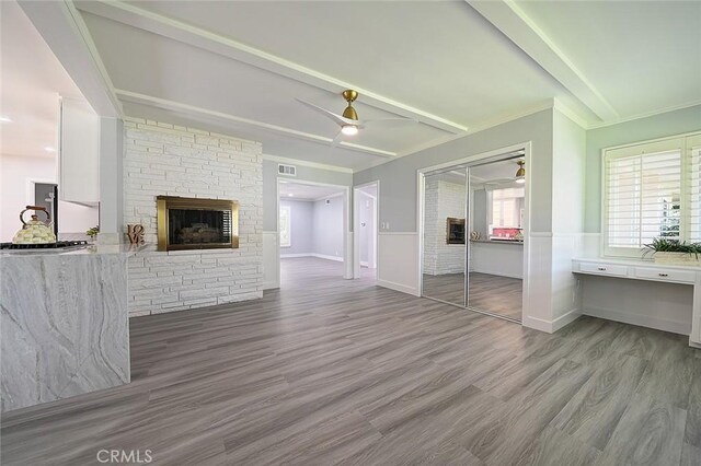 11471 Gill Dr, Garden Grove, CA 92841 - unfurnished living room with wood finished floors, a stone fireplace, wainscoting, a ceiling fan, and beam ceiling