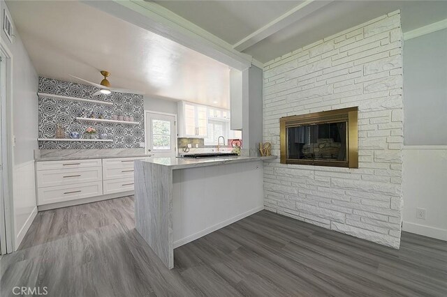 11471 Gill Dr, Garden Grove, CA 92841 - kitchen with white cabinetry, dark wood-style flooring, light countertops, a peninsula, and a fireplace