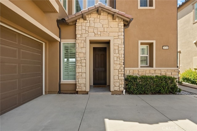 20748 Beech Cir, Porter Ranch, CA 91311 - entrance to property featuring stone siding, concrete driveway, stucco siding, and an attached garage