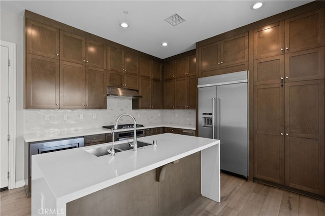 20748 Beech Cir, Porter Ranch, CA 91311 - kitchen with stainless steel built in refrigerator, under cabinet range hood, light wood-style floors, light countertops, and backsplash