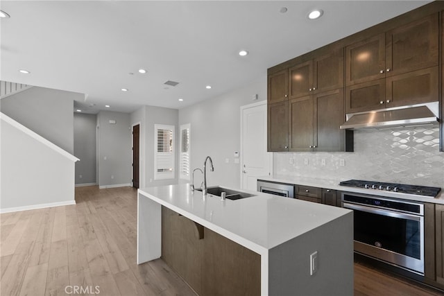 20748 Beech Cir, Porter Ranch, CA 91311 - kitchen with oven, a sink, under cabinet range hood, gas stovetop, and backsplash