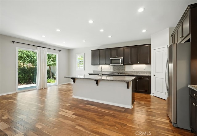 35414 Laurel Tree Ct, Winchester, CA 92596 - kitchen with stainless steel appliances, a breakfast bar, light stone counters, dark wood-style flooring, and recessed lighting