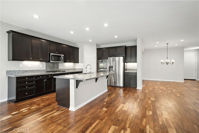 35414 Laurel Tree Ct, Winchester, CA 92596 - kitchen featuring appliances with stainless steel finishes, a breakfast bar, dark wood-style flooring, light stone counters, and tasteful backsplash