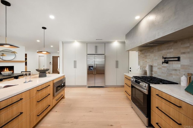 4252 Don Jose Dr, Los Angeles, CA 90008 - kitchen featuring appliances with stainless steel finishes, modern cabinets, tasteful backsplash, light wood-type flooring, and hanging light fixtures