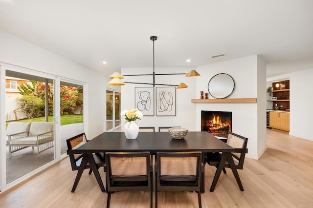 4252 Don Jose Dr, Los Angeles, CA 90008 - dining area with light wood-style flooring, a warm lit fireplace, and recessed lighting