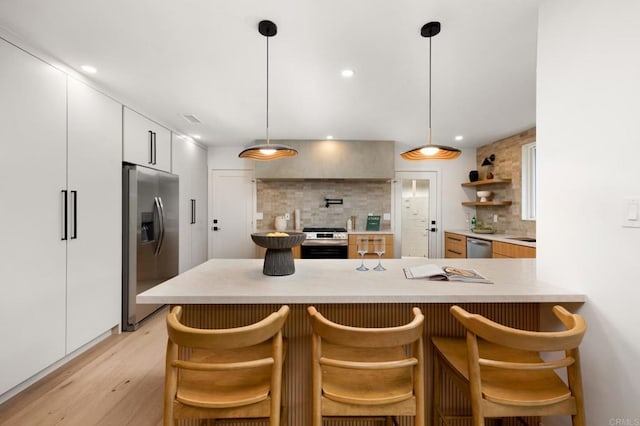 4252 Don Jose Dr, Los Angeles, CA 90008 - kitchen with stainless steel appliances, tasteful backsplash, light wood-style flooring, a peninsula, and white cabinets