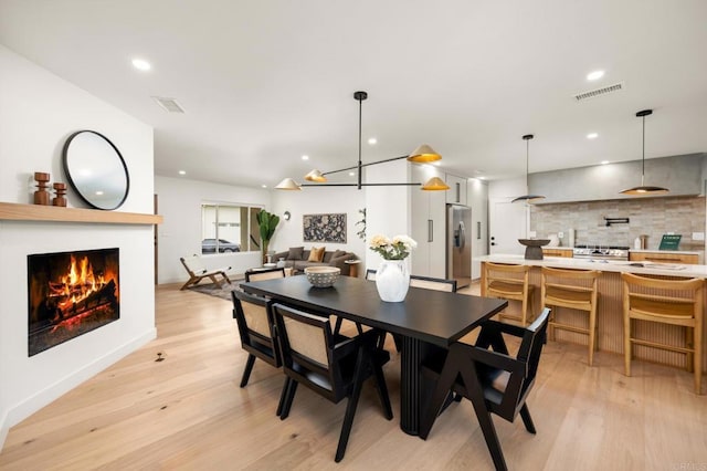 4252 Don Jose Dr, Los Angeles, CA 90008 - dining area featuring light wood-style flooring, a lit fireplace, and recessed lighting