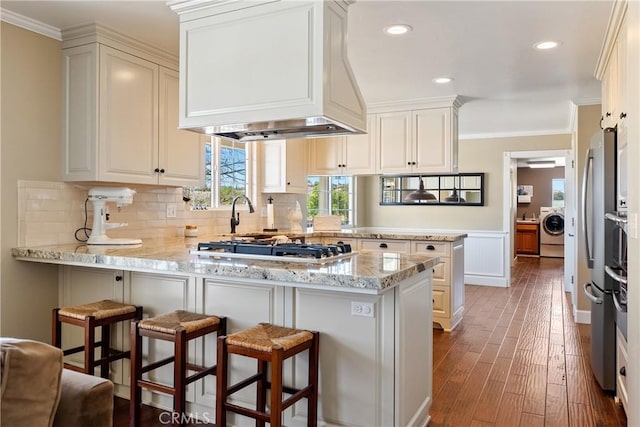 26 Deer View Ln, Templeton, CA 93465 - kitchen with washer / clothes dryer, a peninsula, crown molding, dark wood-style floors, and custom range hood
