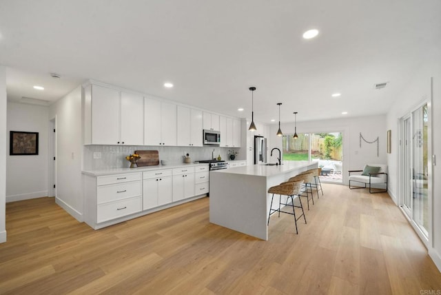 3750 Grecourt Way, Carlsbad, CA 92008 - kitchen with stainless steel appliances, light wood-style flooring, an island with sink, recessed lighting, and a kitchen bar