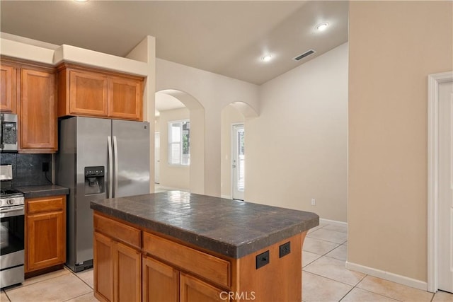 1033 Raven Ln, Chico, CA 95926 - kitchen with appliances with stainless steel finishes, arched walkways, light tile patterned flooring, brown cabinets, and recessed lighting