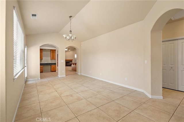 1033 Raven Ln, Chico, CA 95926 - empty room featuring light tile patterned flooring, arched walkways, vaulted ceiling, and baseboards