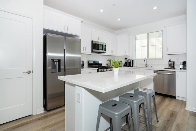 1807 Mesquite Way, Oceanside, CA 92056 - kitchen with appliances with stainless steel finishes, light wood-style flooring, a kitchen bar, white cabinets, and a kitchen island