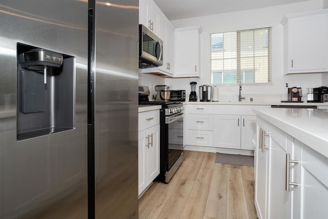 1807 Mesquite Way, Oceanside, CA 92056 - kitchen featuring appliances with stainless steel finishes, light wood-style floors, white cabinetry, light countertops, and a sink
