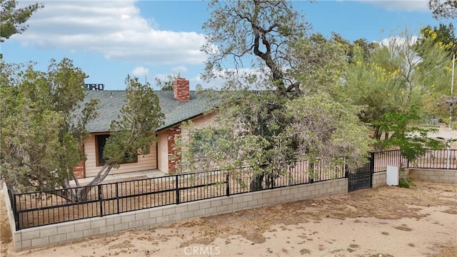 14676 Poplar St, Hesperia, CA 92345 - view of property hidden behind natural elements featuring a shingled roof and a chimney