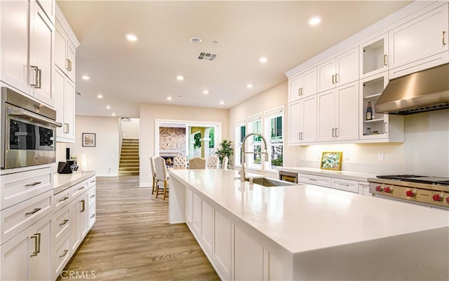 71 Einstein Way, Irvine, CA 92618 - kitchen featuring range hood, a sink, an island with sink, light countertops, and recessed lighting