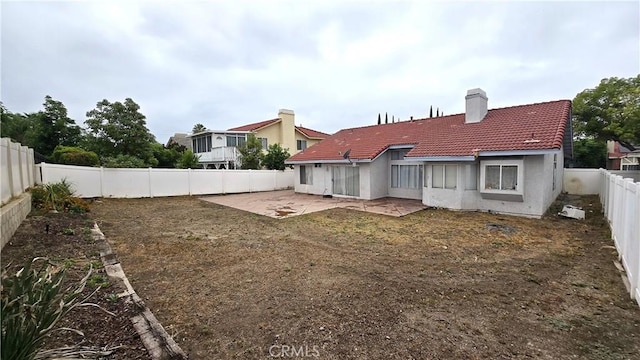 1822 Glover St, Redlands, CA 92374 - back of house featuring a tiled roof, a patio, a fenced backyard, a chimney, and stucco siding