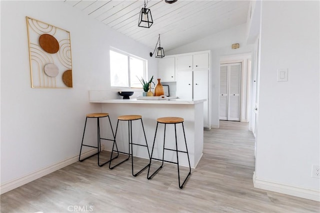 5921 Los Ramos Cir, Buena Park, CA 90620 - kitchen featuring a kitchen breakfast bar, vaulted ceiling, white cabinetry, light wood-style floors, and a peninsula