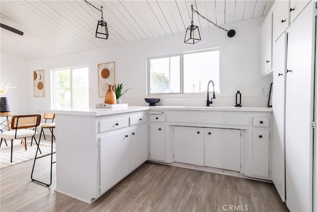 5921 Los Ramos Cir, Buena Park, CA 90620 - kitchen with light wood-style floors, light countertops, white cabinets, a peninsula, and wood ceiling