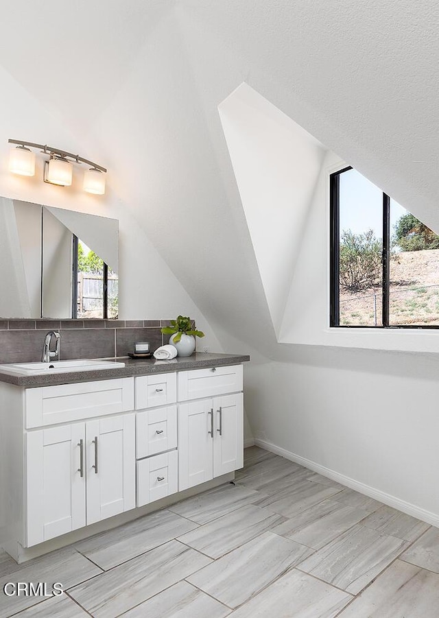4991 Coringa Dr, Highland Park, CA 90042 - full bath featuring double vanity, vaulted ceiling, backsplash, and baseboards
