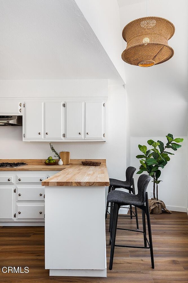 4991 Coringa Dr, Highland Park, CA 90042 - kitchen with wood counters, white cabinetry, wall chimney exhaust hood, and dark wood finished floors
