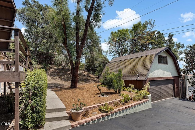 4991 Coringa Dr, Highland Park, CA 90042 - view of side of property featuring a gambrel roof, a garage, roof with shingles, and an outbuilding