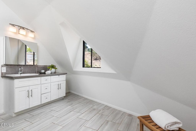 4991 Coringa Dr, Highland Park, CA 90042 - bathroom featuring vanity, backsplash, lofted ceiling, wood finish floors, and baseboards
