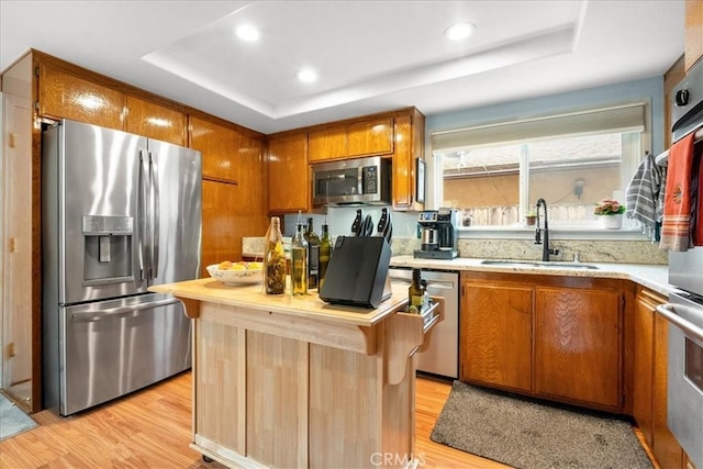 849 Shade Tree Ln, Fallbrook, CA 92028 - kitchen featuring appliances with stainless steel finishes, a sink, a tray ceiling, light wood-style flooring, and recessed lighting