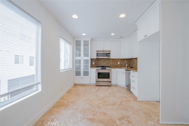 7741 Via Napoli Unit 77, Burbank, CA 91504 - kitchen featuring appliances with stainless steel finishes, tasteful backsplash, white cabinets, recessed lighting, and light stone counters